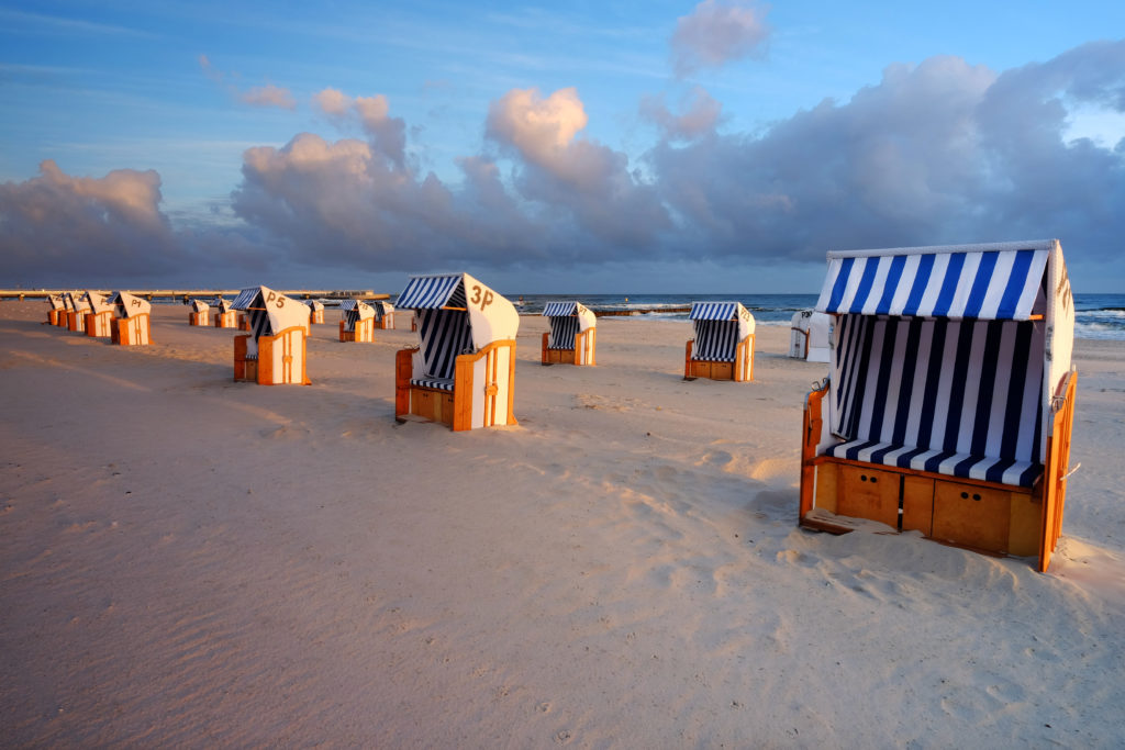 Na zdjęciu widoczne są budki leżakowe postawione na plaży, wszystkie są puste. W tle polskie morze.